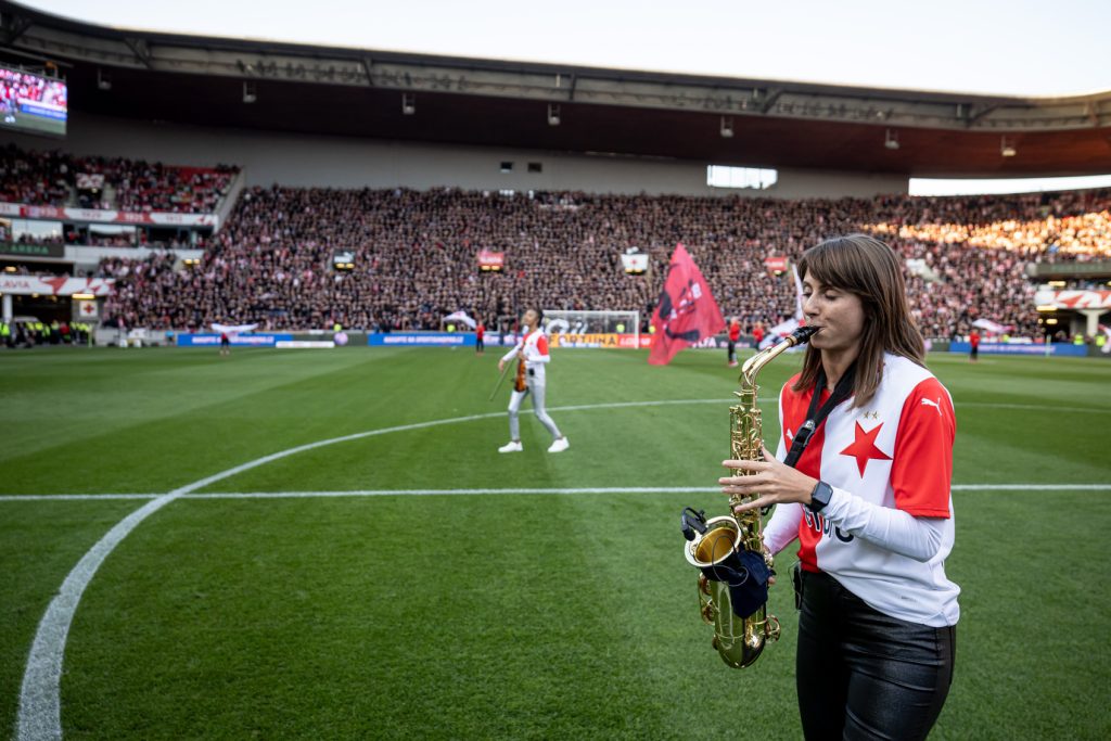 Saxofonistka BURYSAX hraje na trávníku stadionu Eden v Praze před fotbalovým zápasem