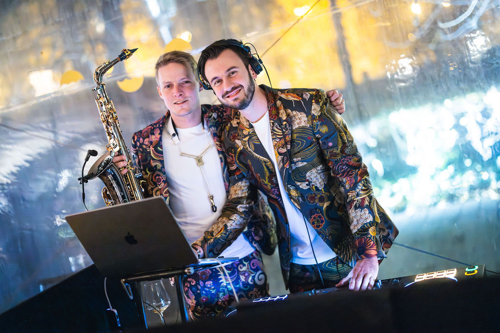 DJ Bury a saxofonista DeeSaxx v ladících sakách za DJ pultem, DJ a saxofonista na firemní večírek